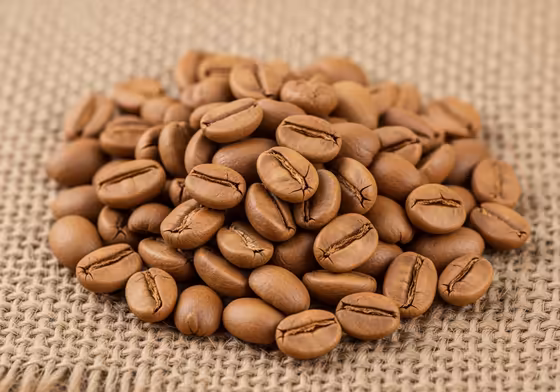 A handful of light roast single-origin Ethiopian coffee beans, showing their lighter brown color and matte surface.