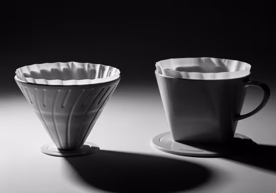 A V-shaped cone coffee filter placed next to a flat-bottomed basket filter to clearly show the difference in shape.